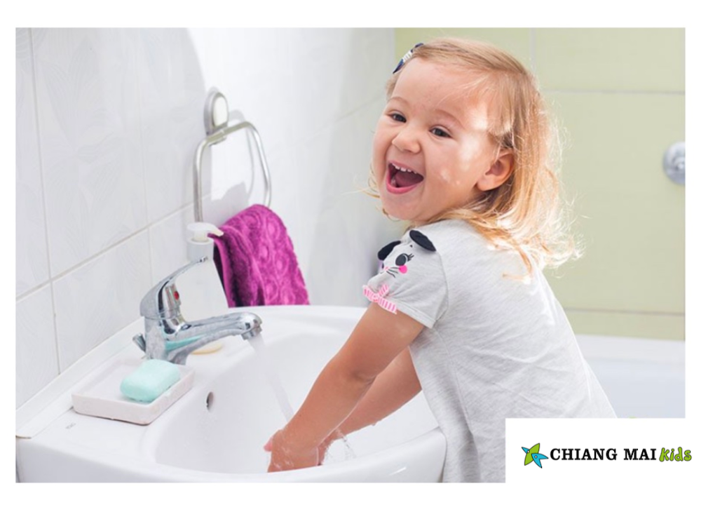 Little girl washing her hands in the bathroom sink