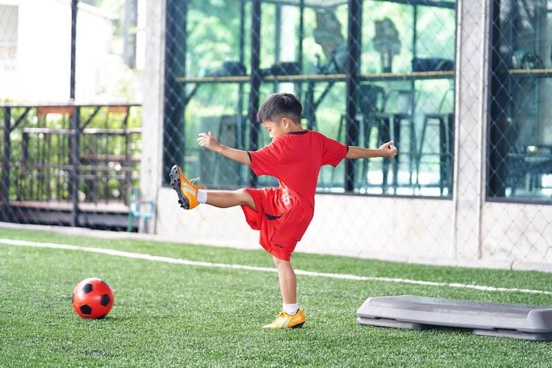 small boy playing football in a garden