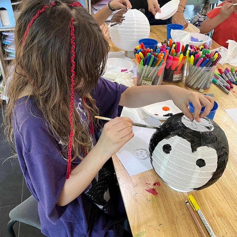 Small girl painting and decorating a lantern